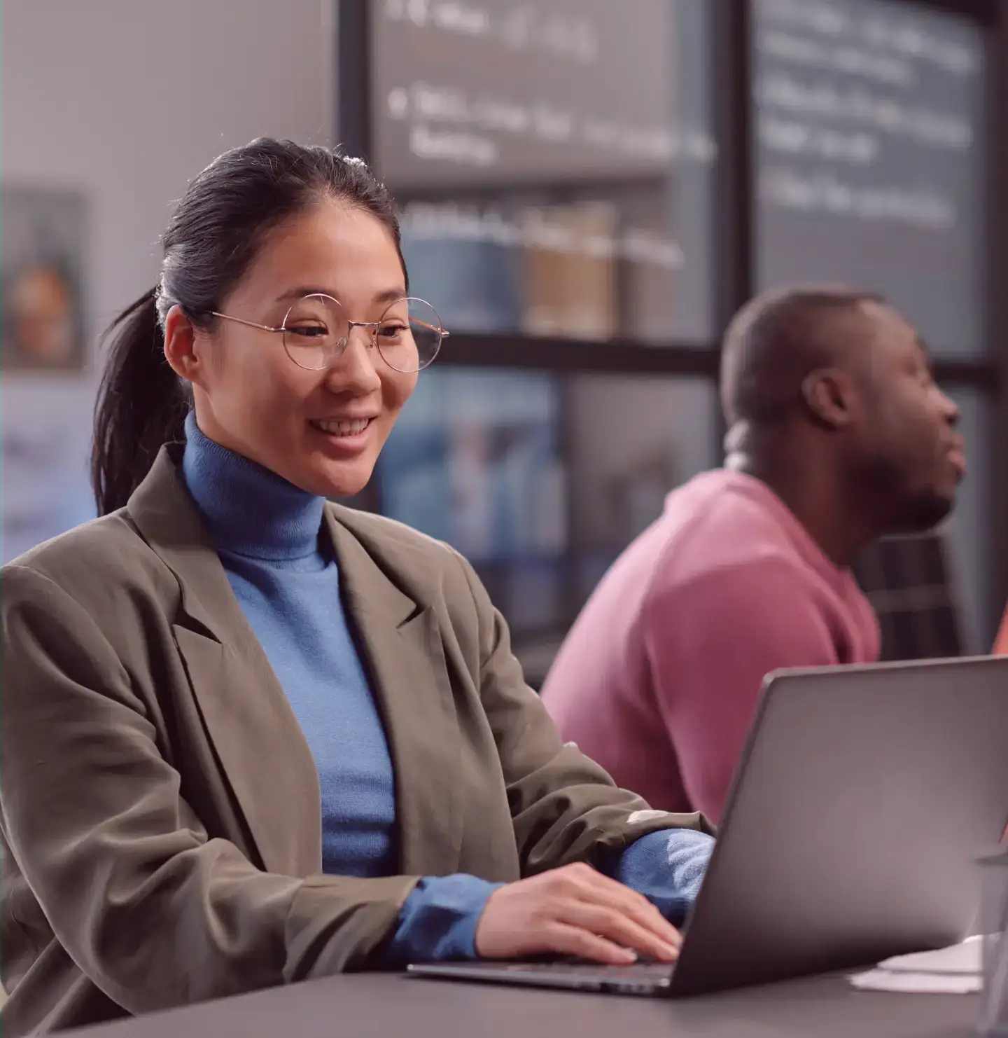 Two colleagues working on laptops in an office