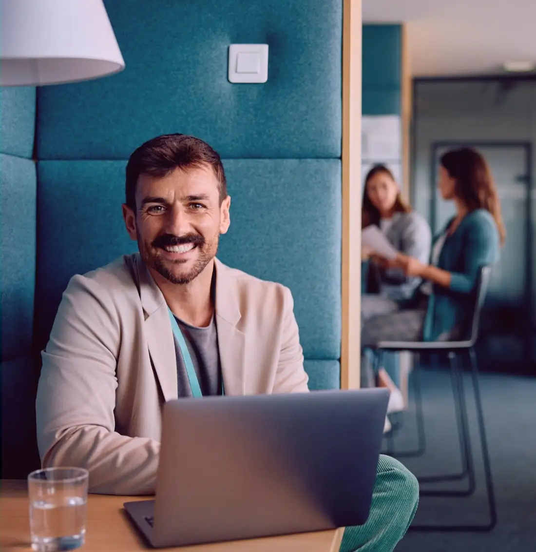 Smiling man with a laptop in a meeting booth